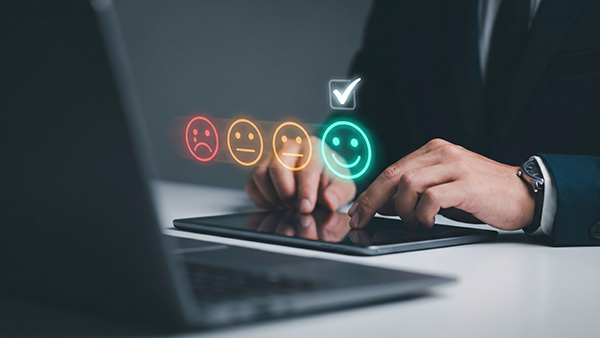 Photo of a man's hands on a tablet with smiley face graphics.