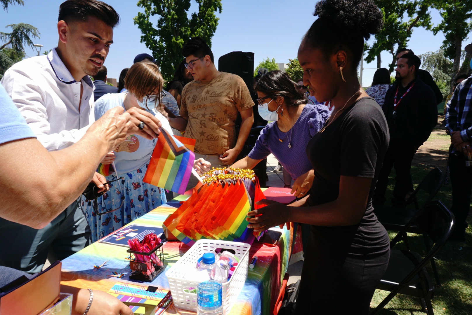 Participants grab small pride flags during the second annual pride flag raising at Fresno State.